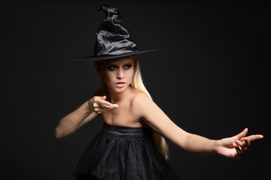 Photo of Witch in black hat on dark background. Scary fantasy character