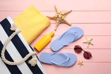 Stylish bag and beach accessories on pink wooden background, flat lay