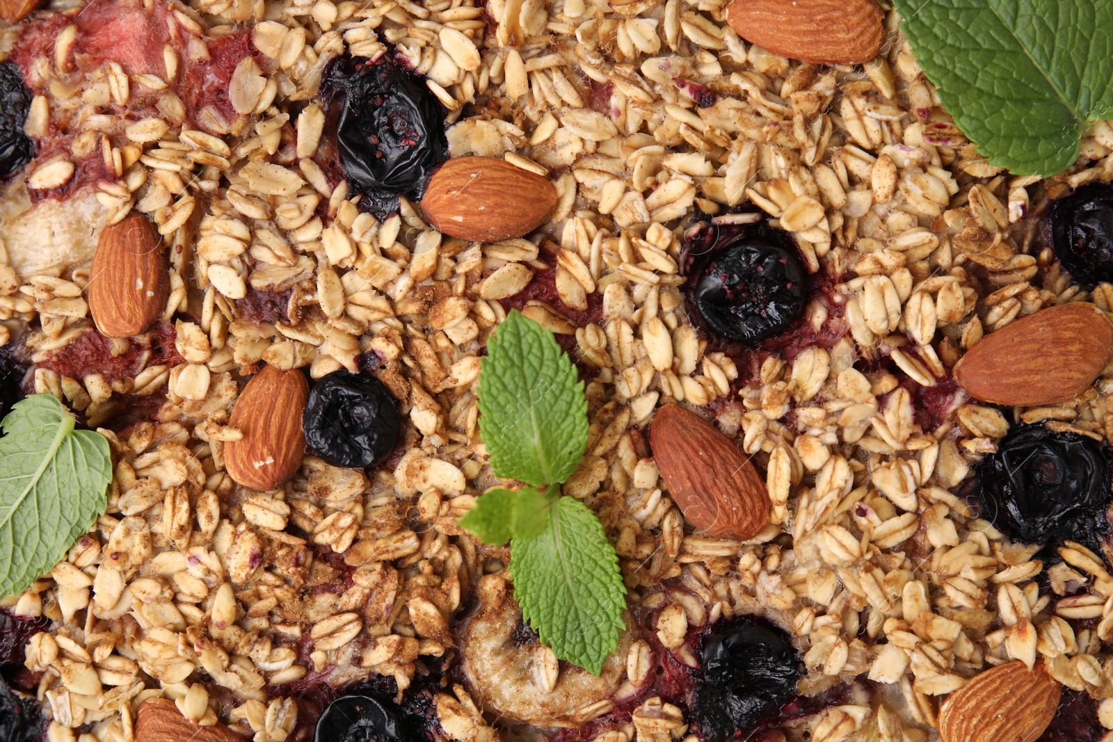 Photo of Tasty baked oatmeal with berries and almonds as background, top view
