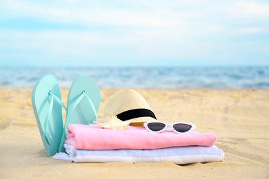 Photo of Different stylish beach objects and seashell on sand near sea