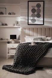 Photo of Soft chunky knit blanket on bed in stylish room interior