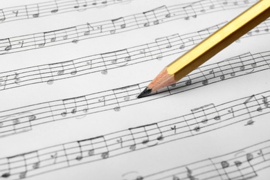 Photo of Sheet with music notes and pencil as background, closeup