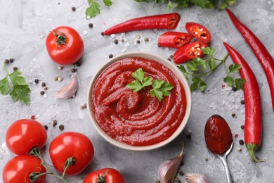 Photo of Flat lay composition with organic ketchup in bowl on grey textured table. Tomato sauce