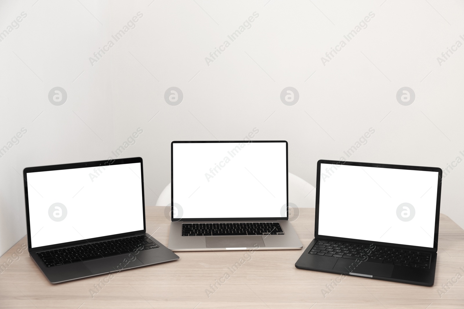 Photo of Different laptops on wooden table. Modern technology