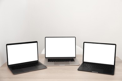 Photo of Different laptops on wooden table. Modern technology