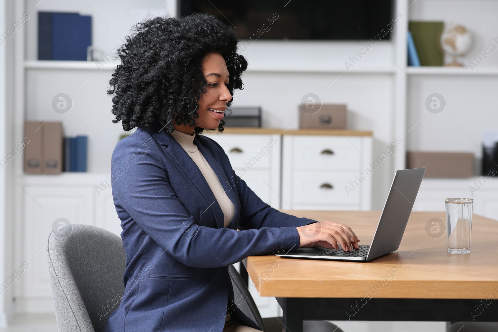 Photo of Young woman working on laptop at table in office