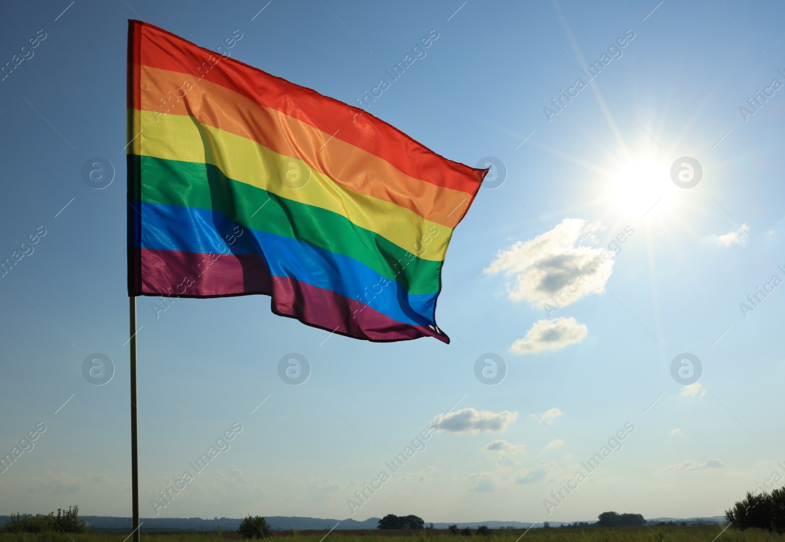 Photo of Bright LGBT flag fluttering against blue sky, space for text. Lesbian concept