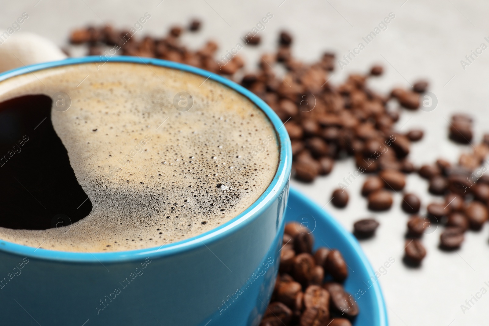 Photo of Cup of aromatic coffee and beans on table, closeup