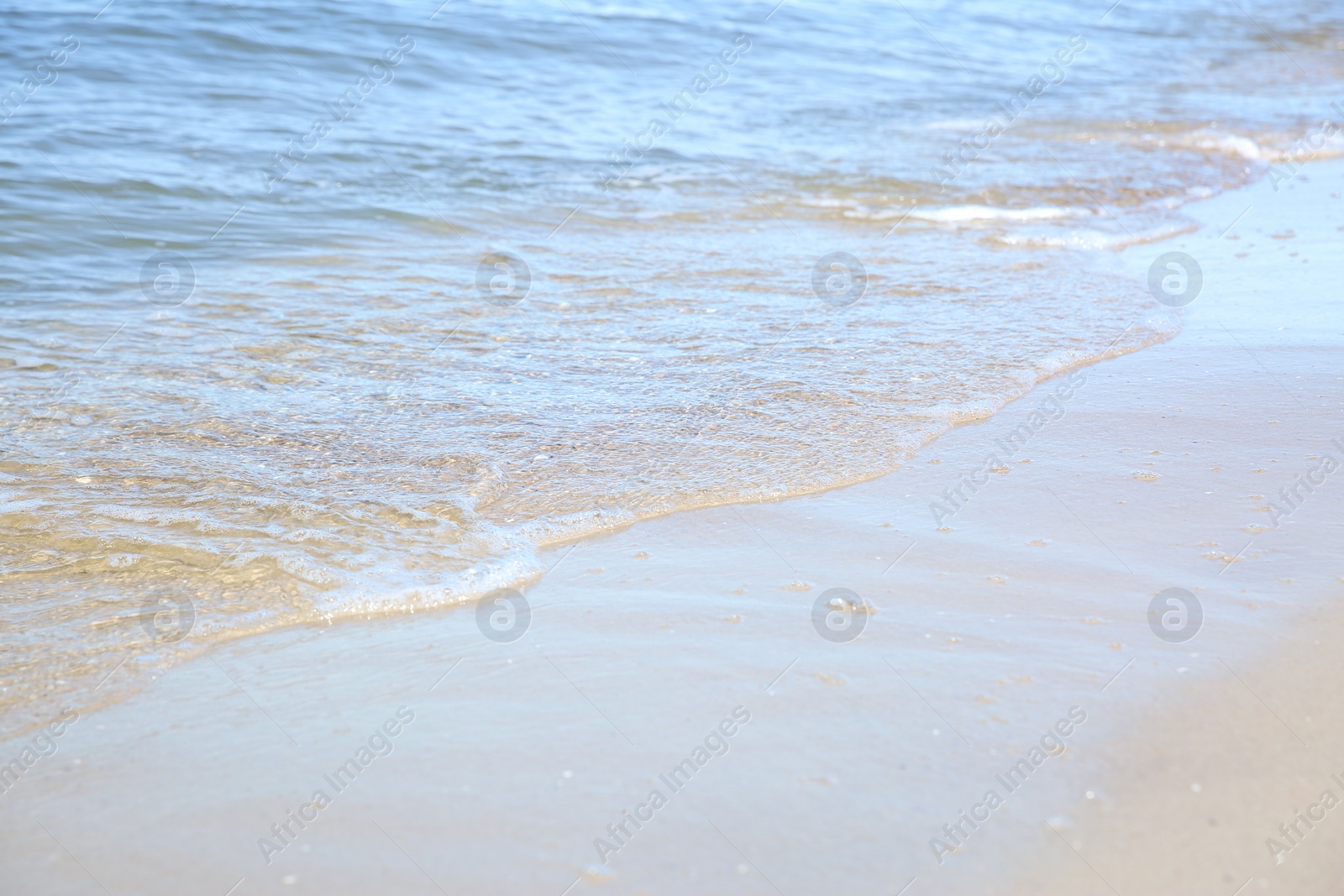 Photo of Beautiful sea waves on sandy beach, closeup