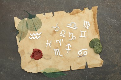 Photo of Zodiac signs, stones and old paper on grey textured table, flat lay
