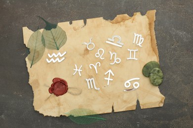 Zodiac signs, stones and old paper on grey textured table, flat lay