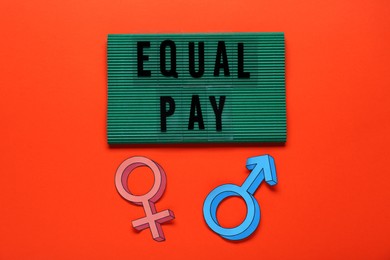Photo of Words Equal Pay and gender symbols on orange background, flat lay