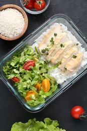 Photo of Healthy meal. Fresh salad, chicken and rice in glass container near other products on black table, flat lay