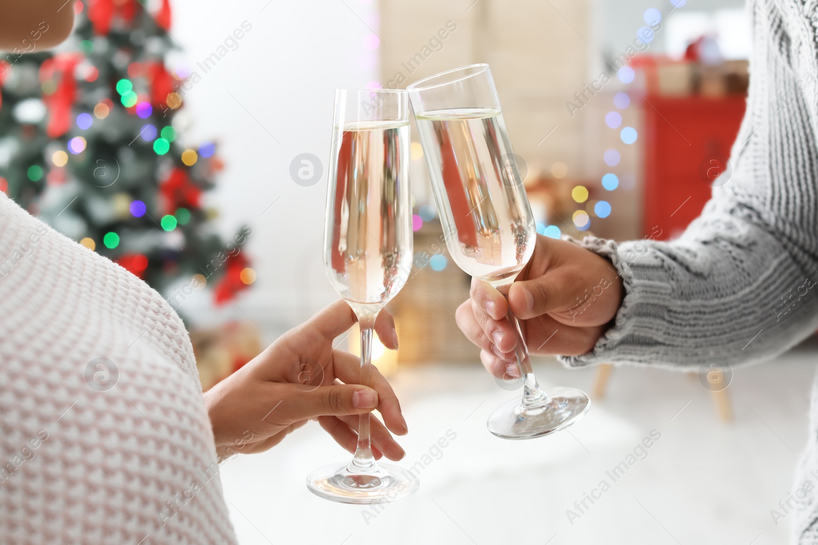 Photo of Happy young couple with glasses of champagne celebrating Christmas at home