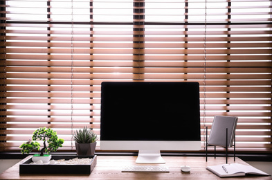 Photo of Modern workplace with beautiful miniature zen garden and computer in room