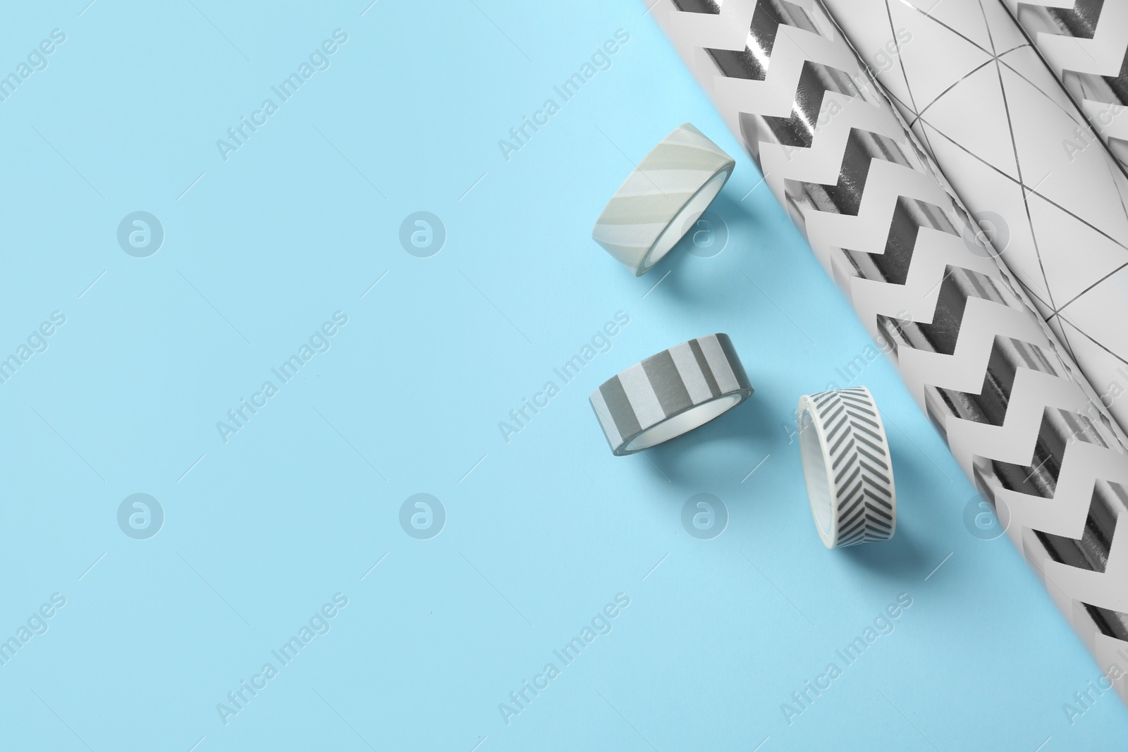 Photo of Wrapping paper rolls and adhesive tapes on color background, top view with space for text. Gift box packaging ideas