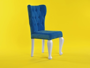 Photo of Stylish blue chair on yellow background. Element of interior design