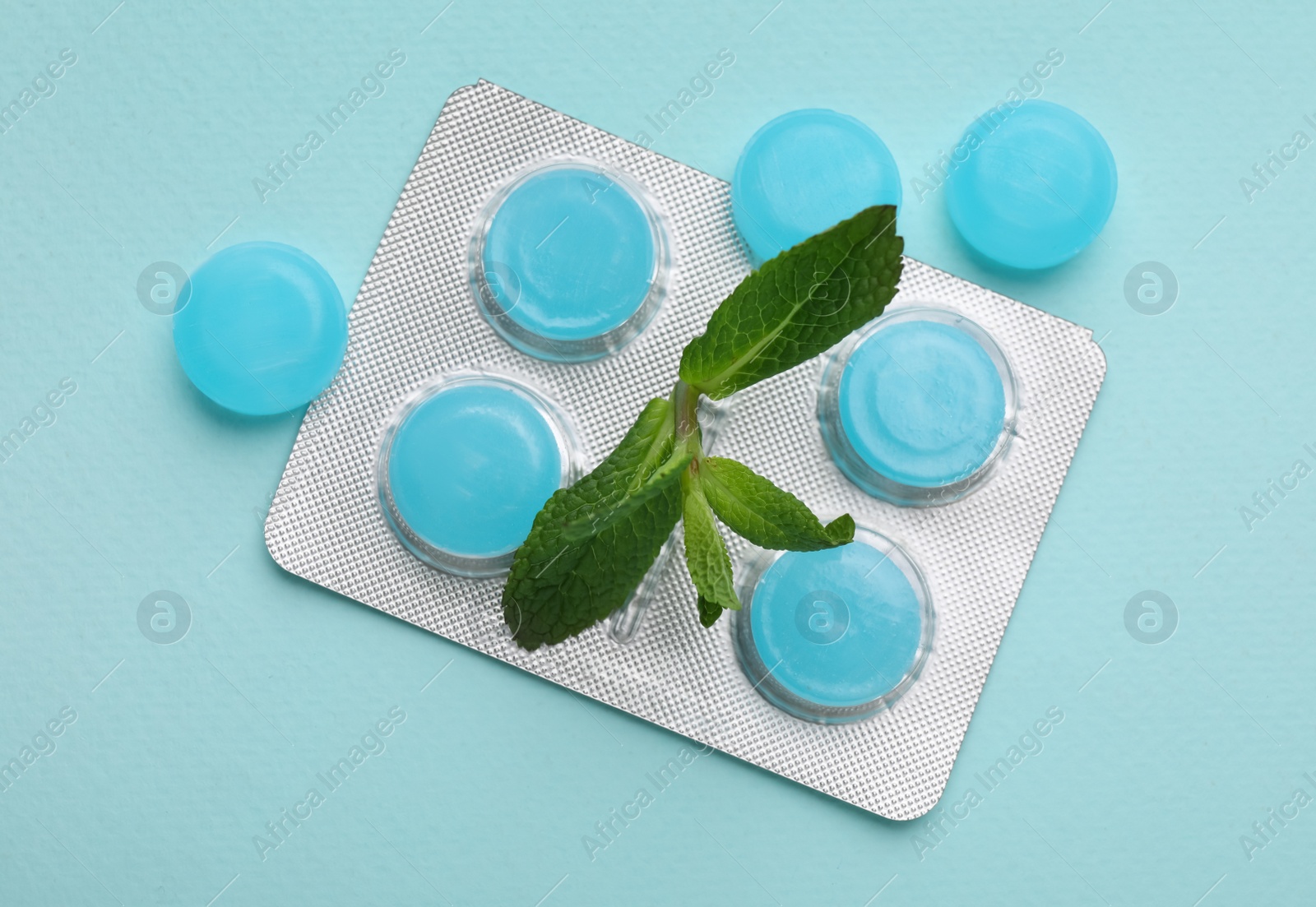Photo of Many cough drops and mint on light blue background, flat lay
