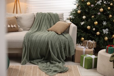 Photo of Sofa near Christmas tree in room. Festive interior design