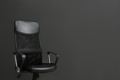 Comfortable office chair on black background. Space for text