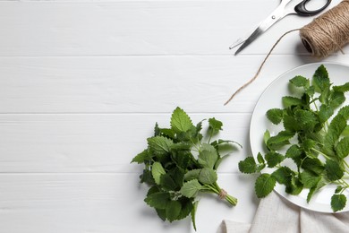 Photo of Fresh lemon balm, scissors and twine on white wooden table, flat lay. Space for text