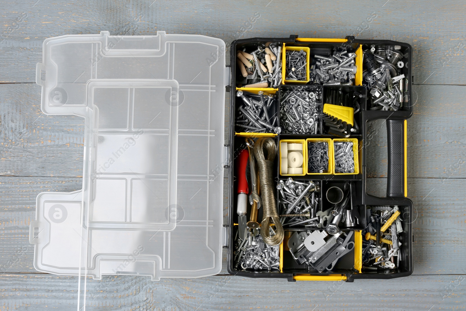 Photo of Box with different furniture fittings and tools on rustic wooden table, top view