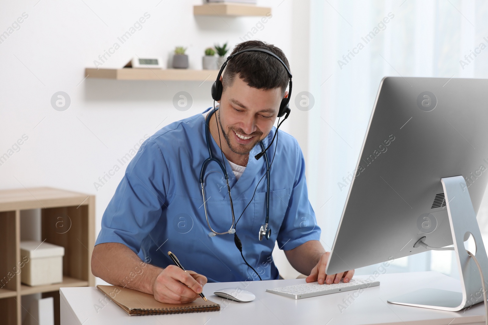 Photo of Doctor with headset consulting patient online at desk in clinic. Health service hotline