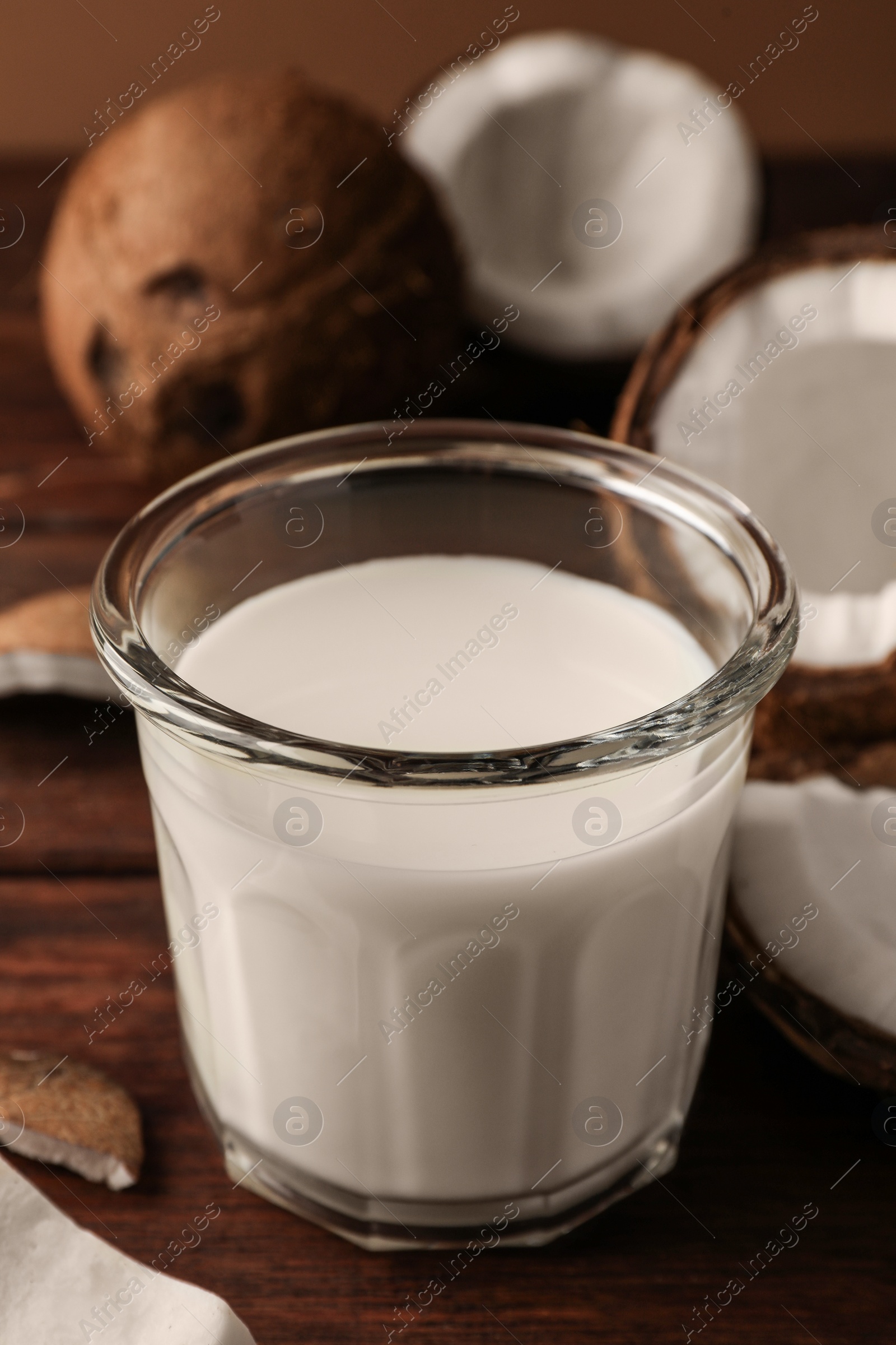 Photo of Glass of delicious vegan milk and coconut pieces on wooden table