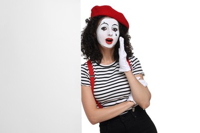 Funny mime with blank poster posing on white background