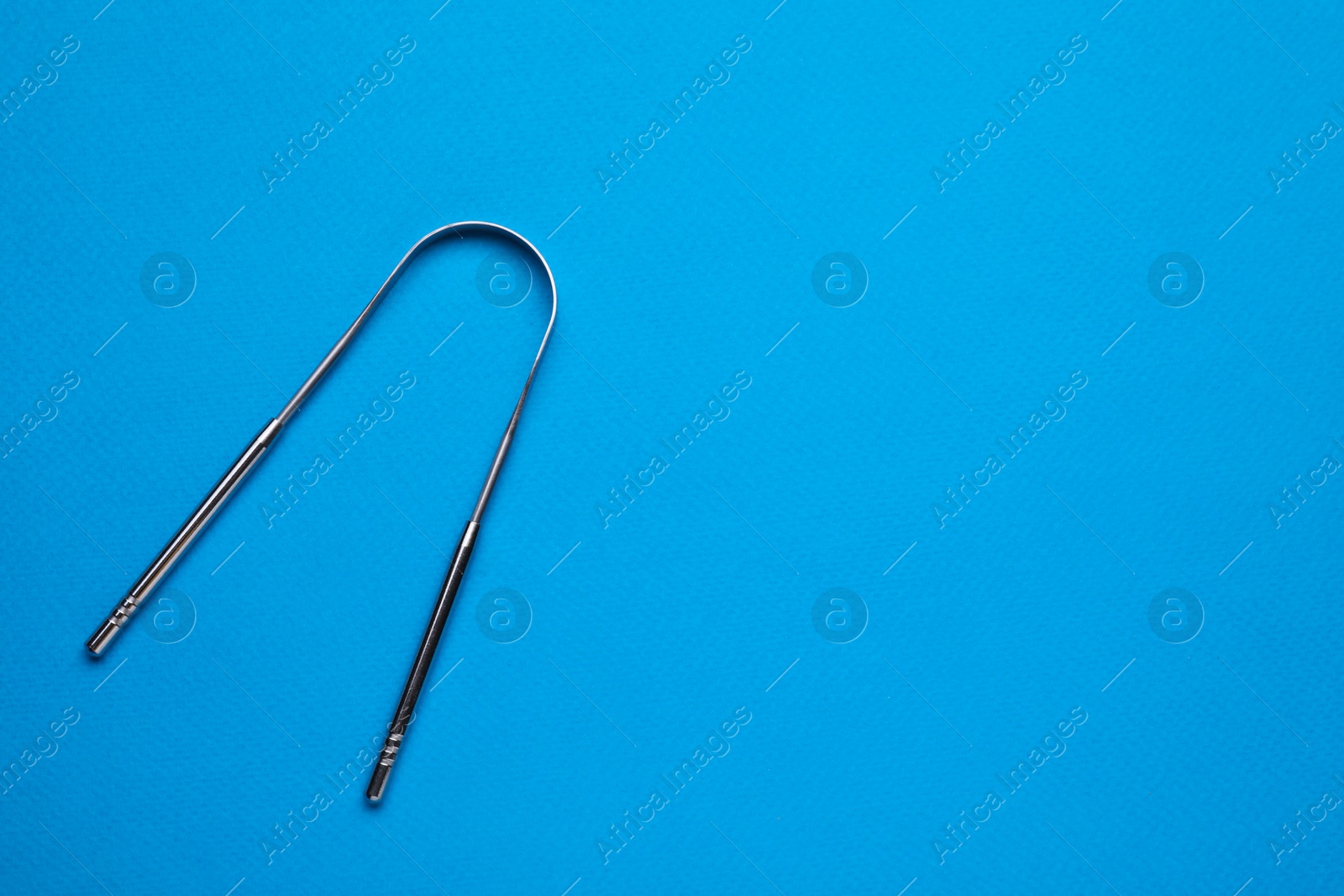 Photo of One tongue cleaner on blue background, top view with space for text. Dental care