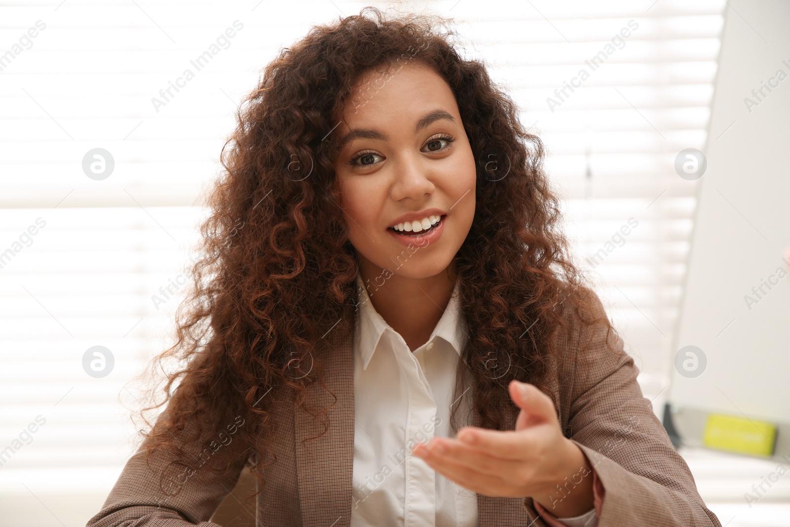 Photo of Happy African-American woman using video chat in office, view from web camera