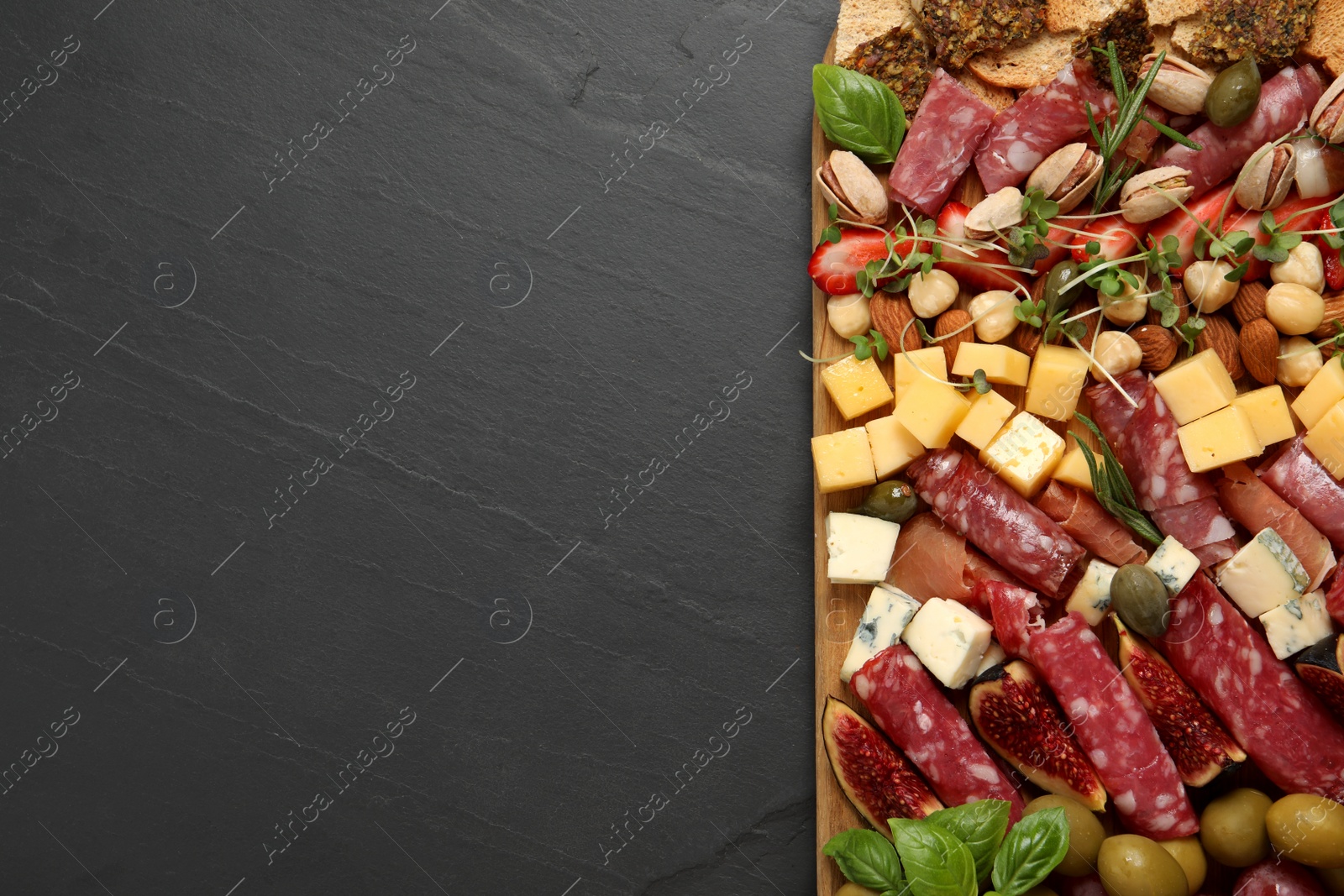 Photo of Different tasty appetizers on dark grey table, top view. Space for text