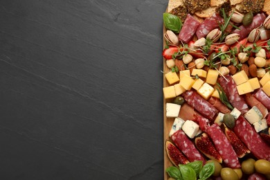 Photo of Different tasty appetizers on dark grey table, top view. Space for text