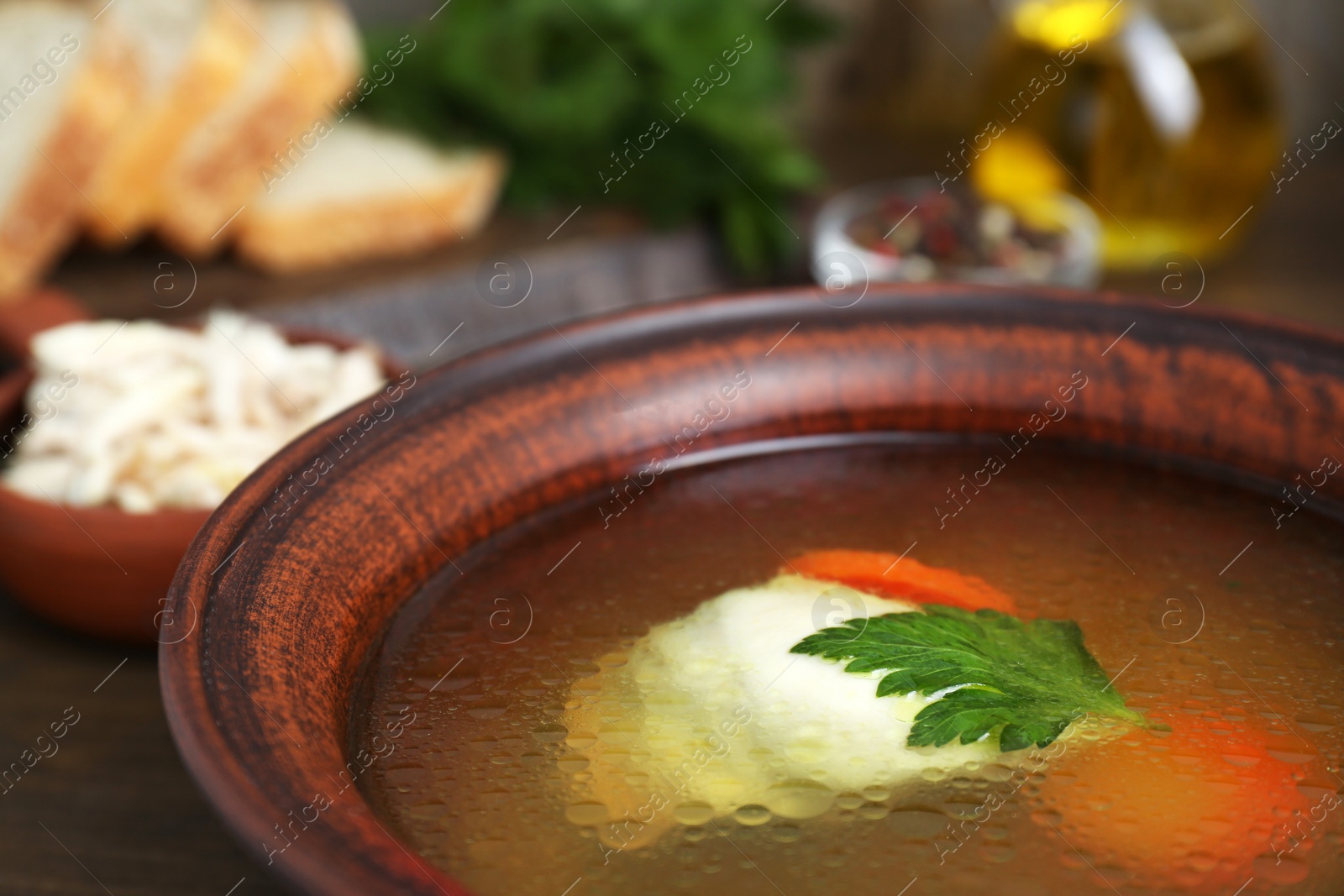 Photo of Delicious chicken bouillon with carrot and parsley in bowl, closeup