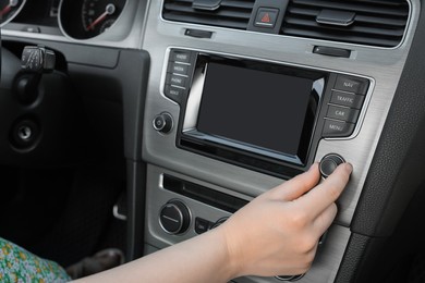 Photo of listening to radio while driving. Woman turning volume button on vehicle audio in car, closeup