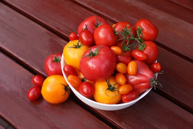 Bowl with fresh tomatoes on wooden table, above view