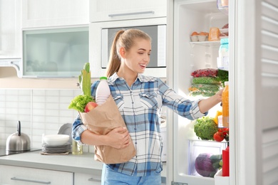 Woman putting products into refrigerator in kitchen