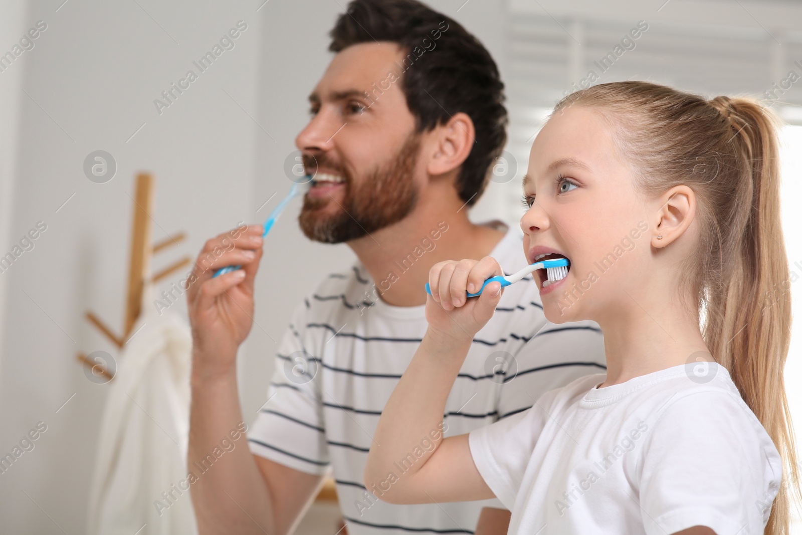 Photo of Father and his daughter brushing teeth together in bathroom