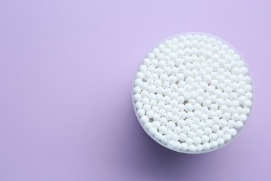 Photo of Many cotton buds in container on violet background, top view. Space for text