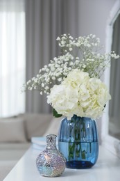 Photo of Stylish catalytic lamp with beautiful bouquet on white table in living room. Cozy interior