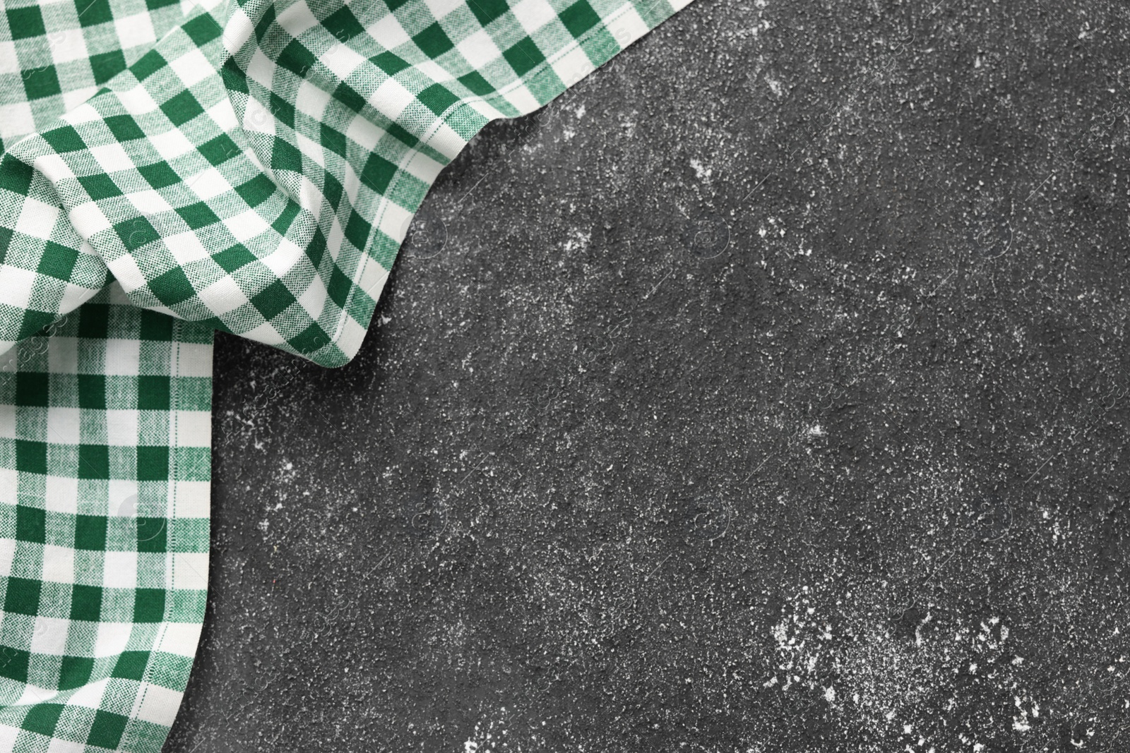 Photo of Green checkered tablecloth on black textured table, top view. Space for text