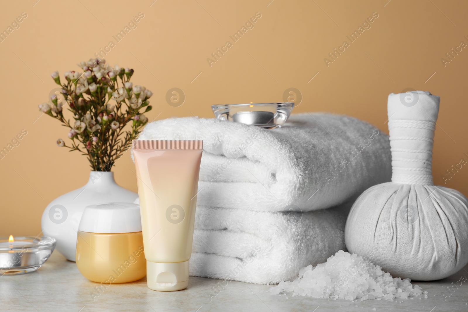 Photo of Composition with different spa products, candles and flowers on beige table