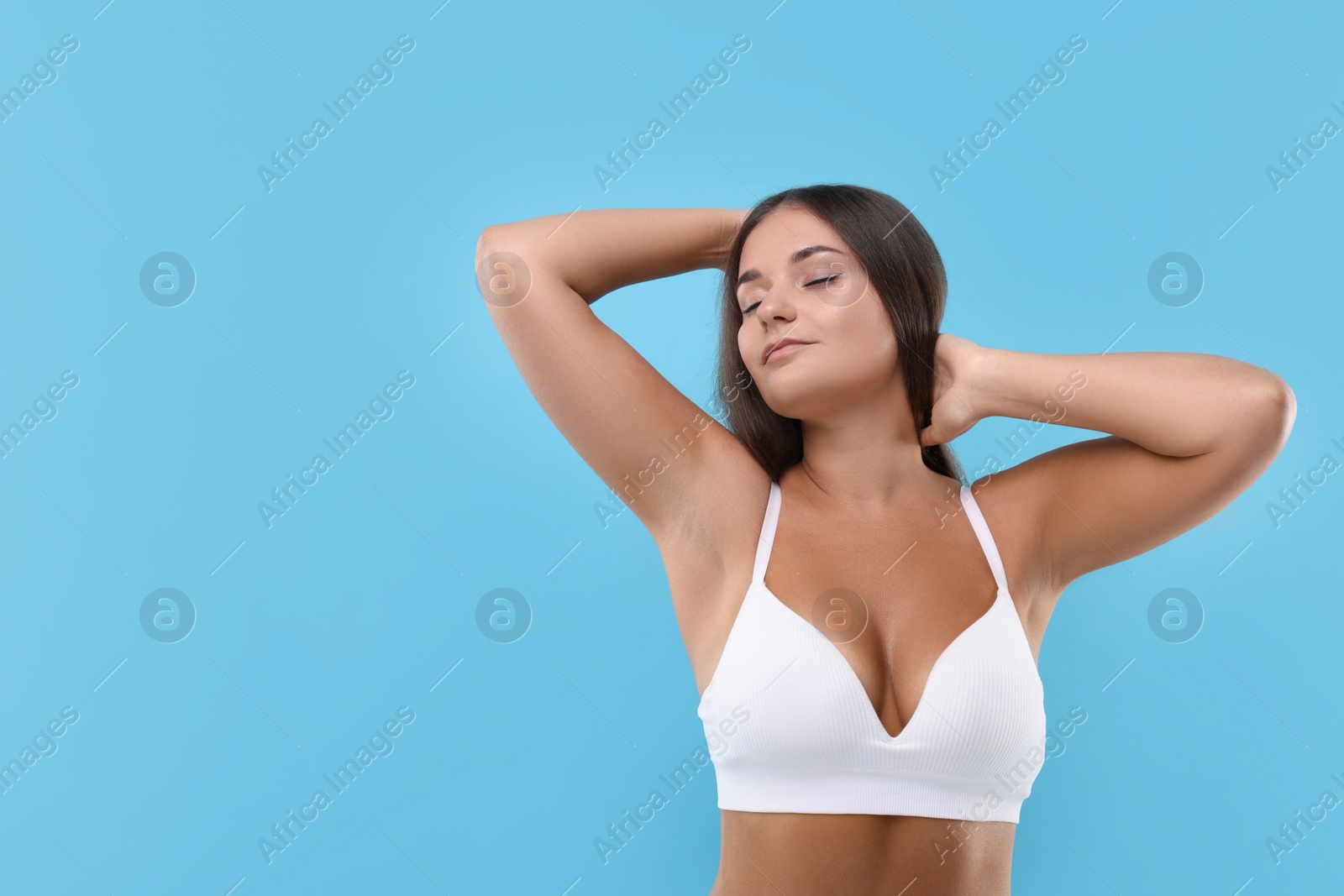 Photo of Portrait of young woman with beautiful breast on light blue background. Space for text