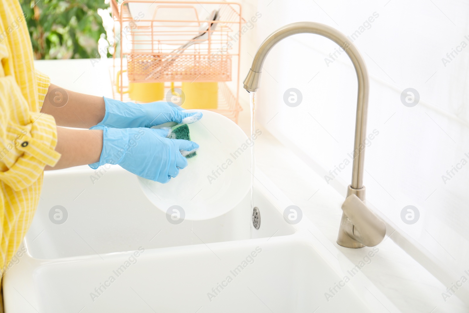 Photo of Woman washing ceramic plate in kitchen, closeup