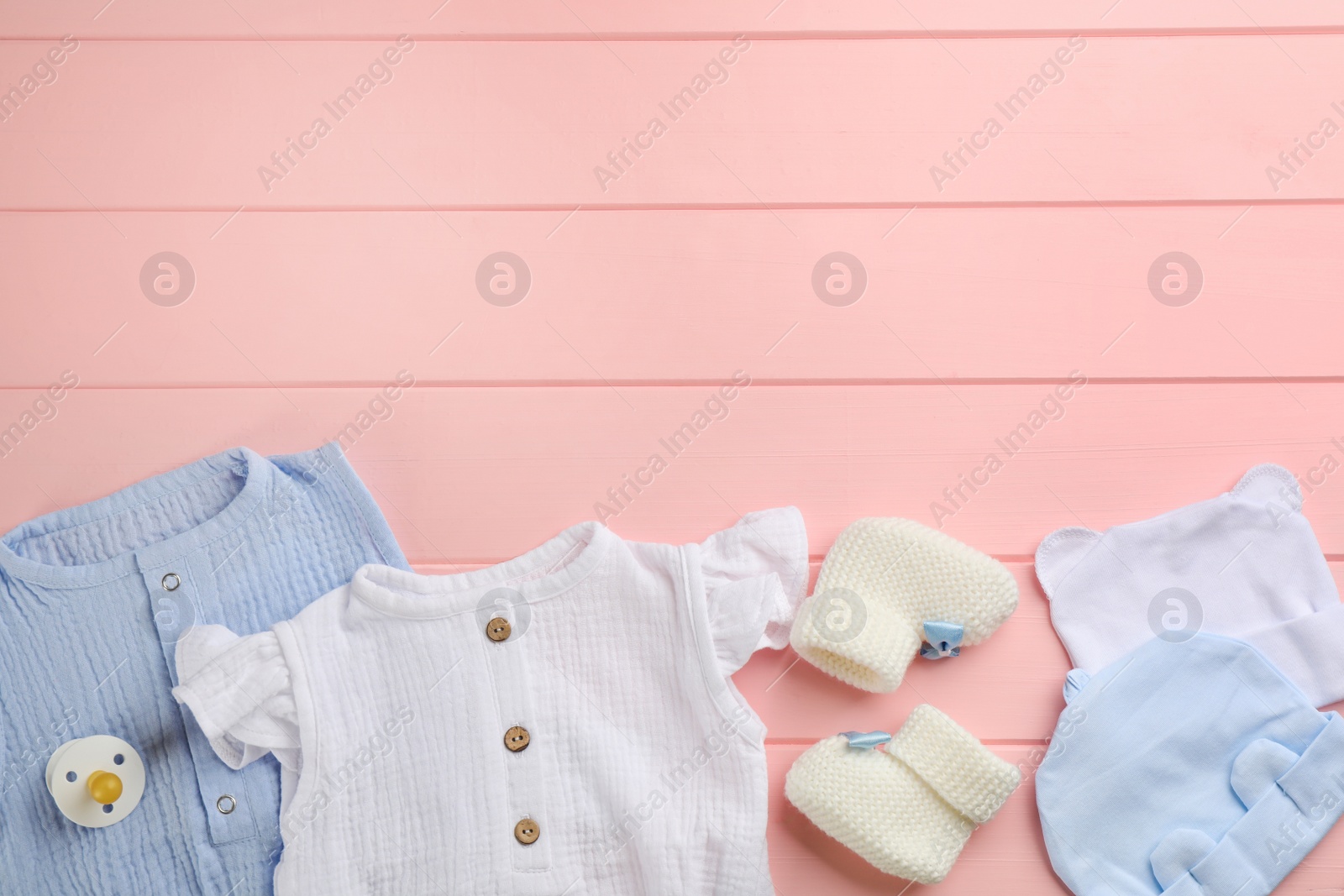 Photo of Flat lay composition with baby clothes and accessories on pink wooden background, space for text