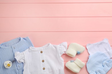 Flat lay composition with baby clothes and accessories on pink wooden background, space for text