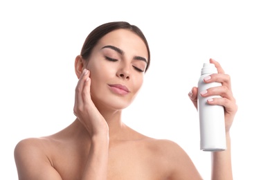 Young woman applying thermal water on face against white background. Cosmetic product