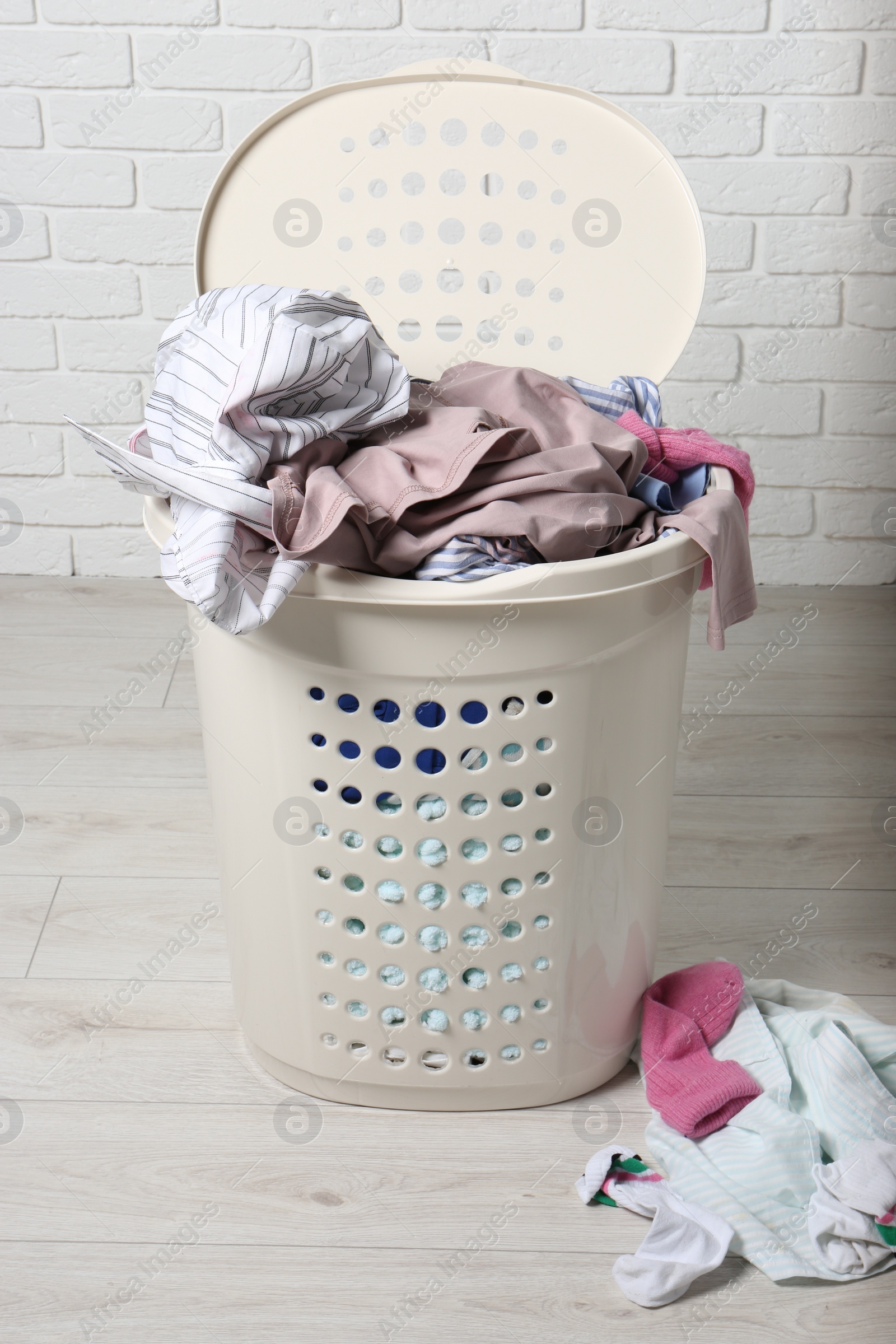 Photo of Laundry basket with clothes near white brick wall