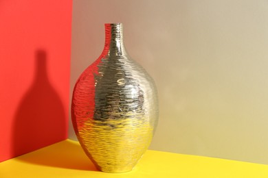 Stylish silver ceramic vase on color background