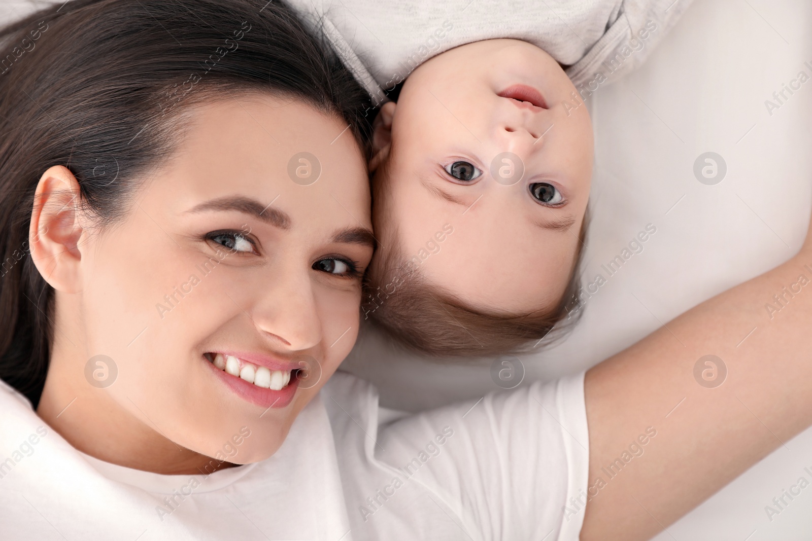 Photo of Portrait of mother with her cute baby lying on bed, top view